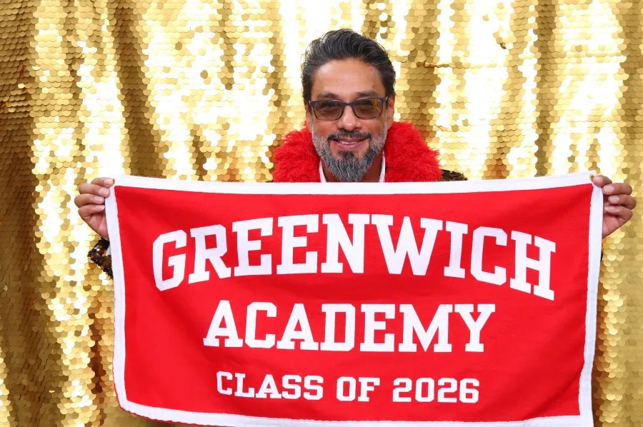 Guest at the gold sequin photo booth holding a Greenwich Academy Class of 2026 sign at Belle Haven Club